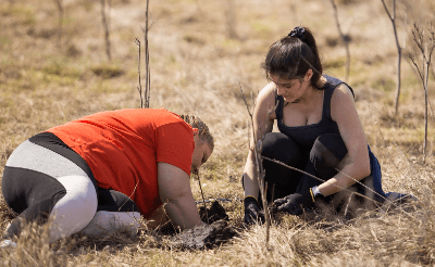 Photo of Andreea with a colleague planting a sapling
