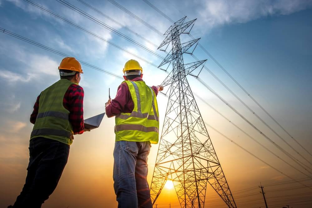 image de deux hommes regardant une ligne électrique