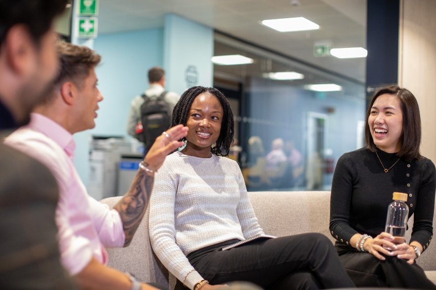 Four AtkinsRéalis colleagues, two men and two women, of varied ethnic backgrounds, talking and smiling in a group