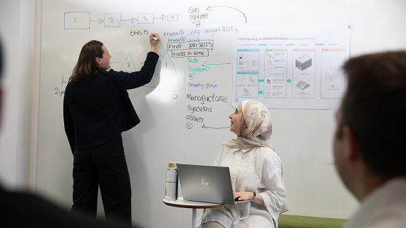 two women collaborating at a whiteboard during a brainstorming session.