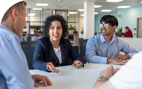 Team members having an engaging discussion around a table in a modern office setting.