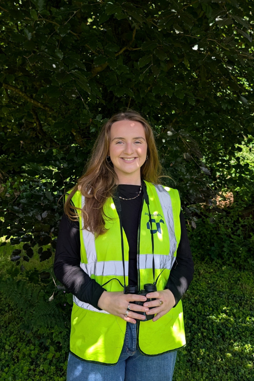 Caroline wearing a high vis AtkinsRéalis jacket, smiling at the camera