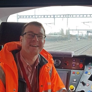 Garry in a railway signalling box wearing an orange jacket and smiling