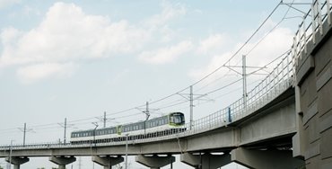 train running on a raised track against a blue sky