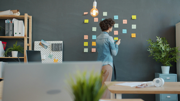 person standing against dark wall looking at sticky notes