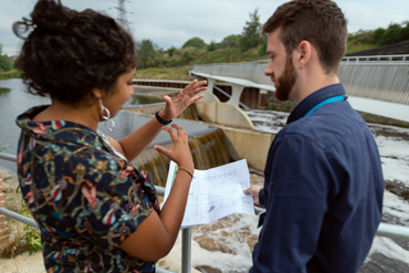 a man and a woman looking at and discussing plans on a site