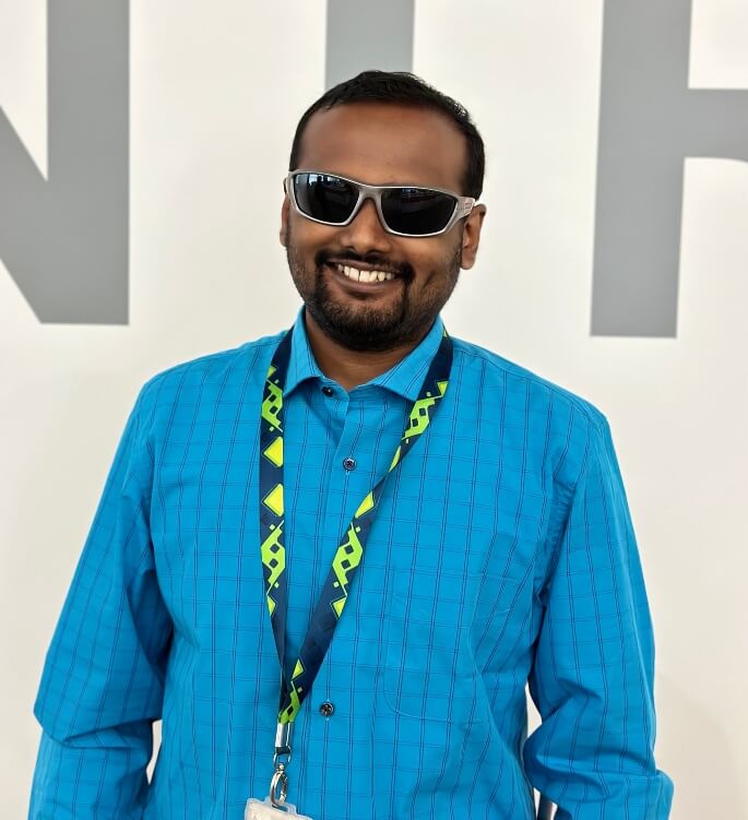 Giridhar posing for the camera in the office premise with a coulourful background