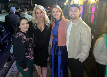 Picture of three women and  a man smiling at the camera