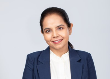 A headshot of Nidhie smiling in a formal attire