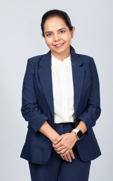 A portrait picture of Nidhie smiling in a formal attire