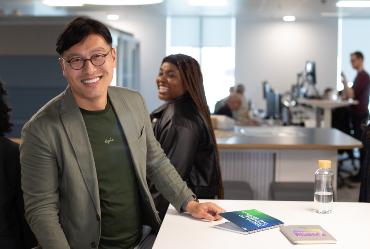 a smiling man leaning towards the camera in AtkinsRéalis office