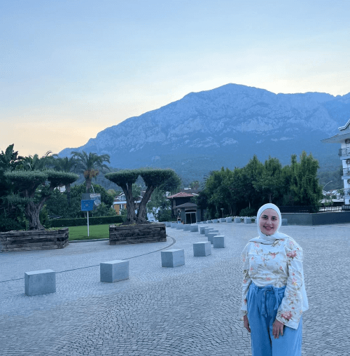 A picture of Omaya smiling with beautiful mountains in the background